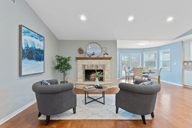 living room with lofted ceiling, a fireplace, and light wood-type flooring