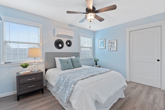 bedroom featuring light hardwood / wood-style flooring, a wall unit AC, and ceiling fan