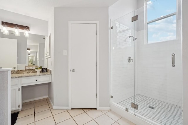 full bath with tile patterned flooring, vanity, a stall shower, and baseboards