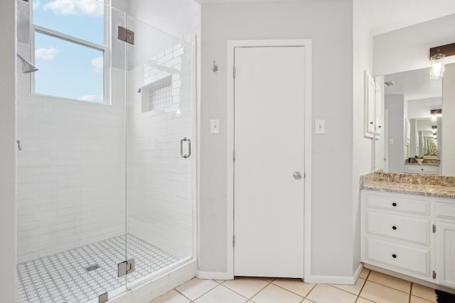 full bathroom with tile patterned flooring, vanity, a stall shower, and baseboards