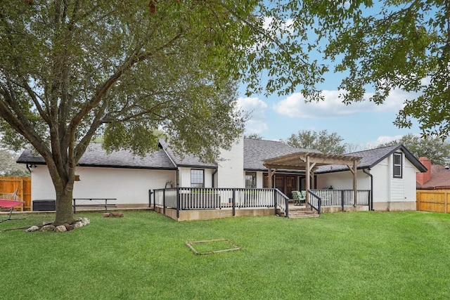 back of property featuring fence, a pergola, roof with shingles, and a lawn