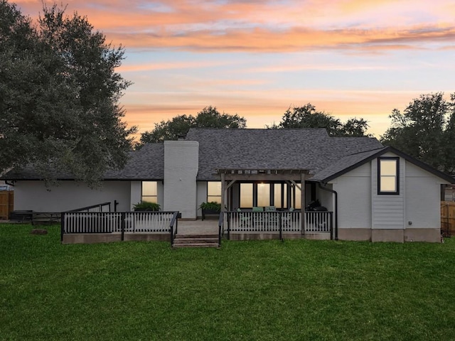 back of property featuring a patio area, a lawn, and roof with shingles