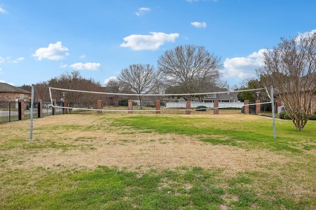 view of home's community with a yard, volleyball court, and fence