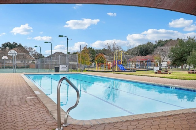 view of pool featuring playground community, community basketball court, and fence