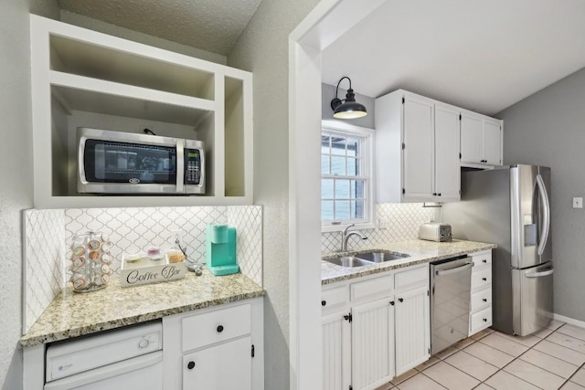 kitchen featuring tasteful backsplash, light stone countertops, white cabinets, stainless steel appliances, and a sink