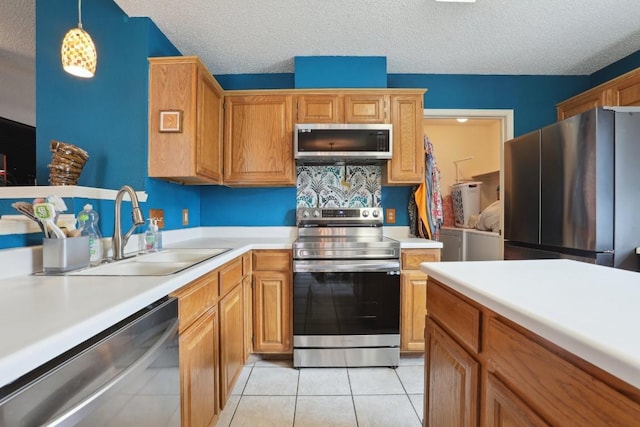 kitchen featuring light countertops, a sink, a textured ceiling, and stainless steel appliances