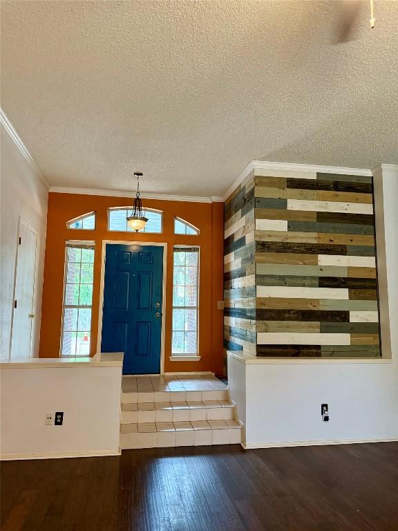 entrance foyer with crown molding, wood-type flooring, and a textured ceiling