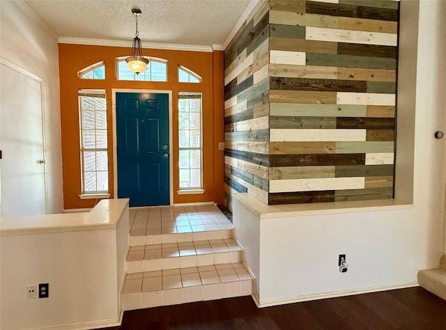 foyer entrance featuring crown molding, wooden walls, a textured ceiling, and a healthy amount of sunlight