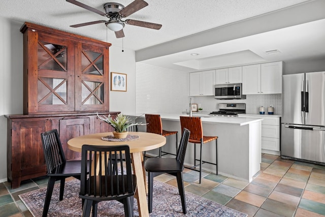 dining area featuring ceiling fan and a textured ceiling