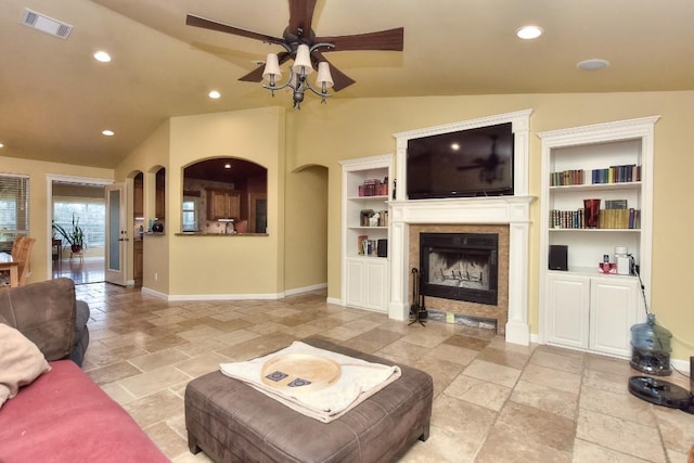 living room featuring built in shelves, ceiling fan, and lofted ceiling