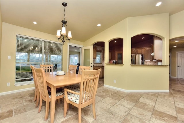 dining area featuring vaulted ceiling and an inviting chandelier