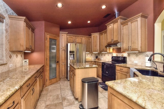 kitchen featuring sink, a center island, stainless steel fridge, black range with electric cooktop, and light stone countertops