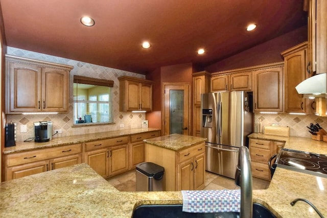 kitchen featuring electric stove, stainless steel fridge, light stone countertops, and a kitchen island