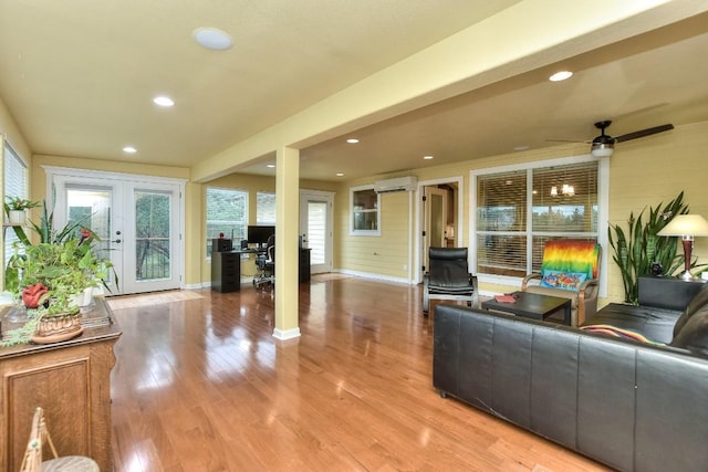 living room featuring french doors, a wall unit AC, and light hardwood / wood-style flooring