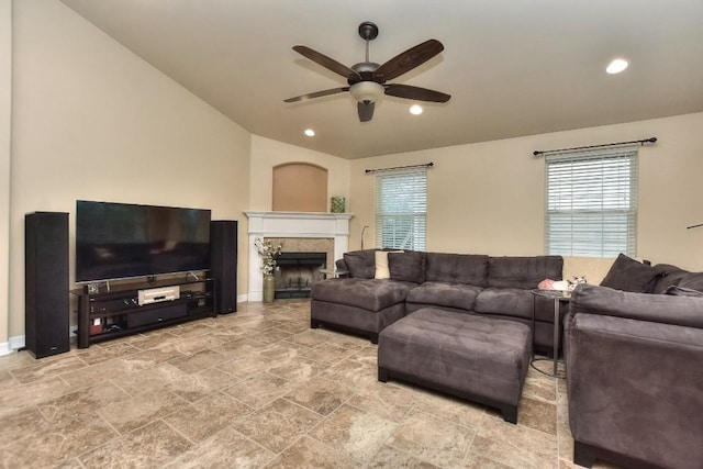 living room with vaulted ceiling, a tile fireplace, plenty of natural light, and ceiling fan