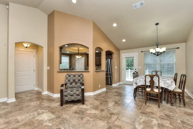 dining area featuring an inviting chandelier and high vaulted ceiling