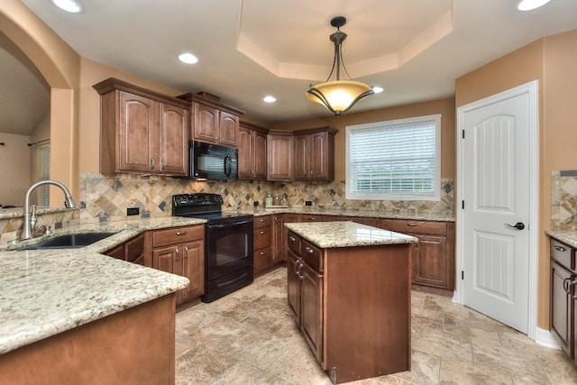 kitchen featuring sink, decorative light fixtures, a tray ceiling, light stone countertops, and black appliances