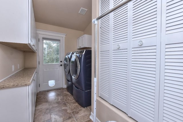 clothes washing area featuring separate washer and dryer and cabinets