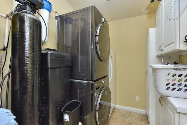 washroom with cabinets, light tile patterned flooring, and stacked washer and clothes dryer