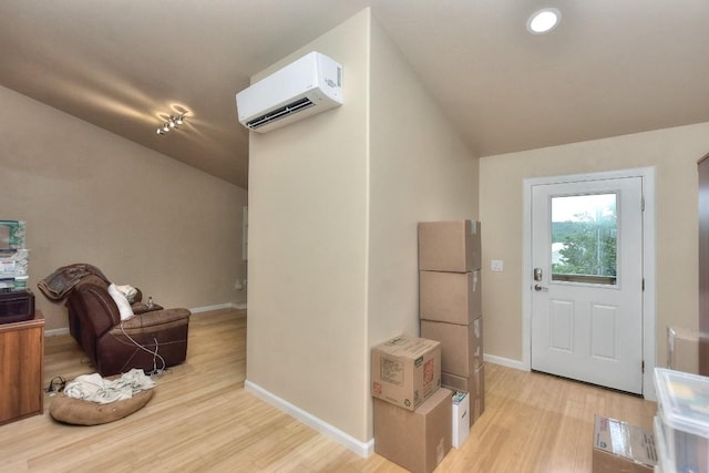 foyer featuring vaulted ceiling, a wall mounted AC, and light wood-type flooring