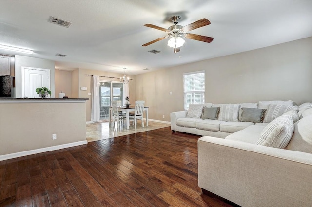 living area with visible vents, baseboards, ceiling fan with notable chandelier, and wood finished floors