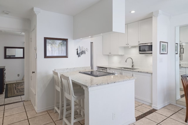 kitchen featuring tasteful backsplash, sink, white cabinets, and light stone counters