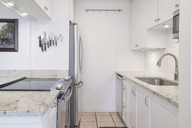 kitchen with sink, white cabinetry, stainless steel appliances, tasteful backsplash, and light stone countertops