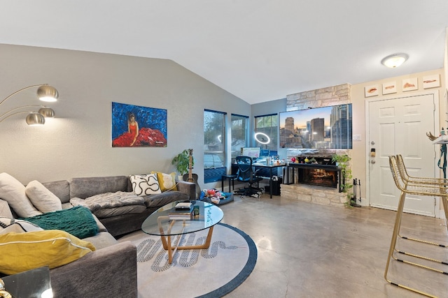 living room featuring lofted ceiling, a stone fireplace, and concrete flooring