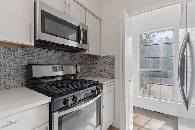 kitchen featuring stainless steel appliances, white cabinetry, and decorative backsplash