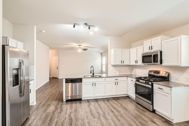 10801 Dimitrios Dr, Austin, TX 78747 - kitchen featuring appliances with stainless steel finishes, ceiling fan, white cabinets, decorative backsplash, and light wood-type flooring