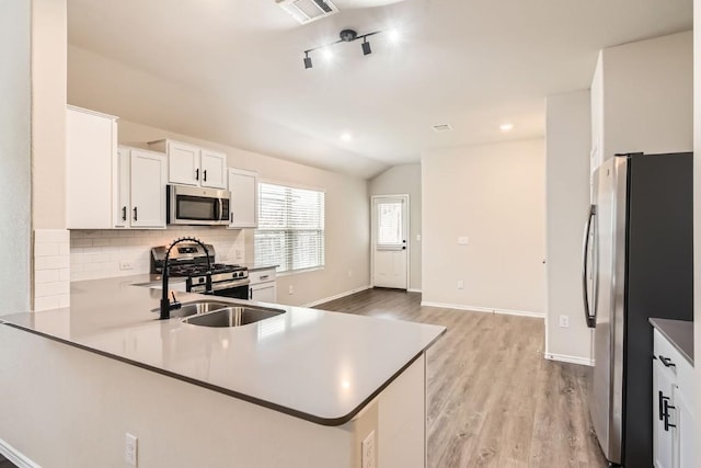 10801 Dimitrios Dr, Austin, TX 78747 - kitchen with appliances with stainless steel finishes, backsplash, light wood-style flooring, white cabinets, and vaulted ceiling