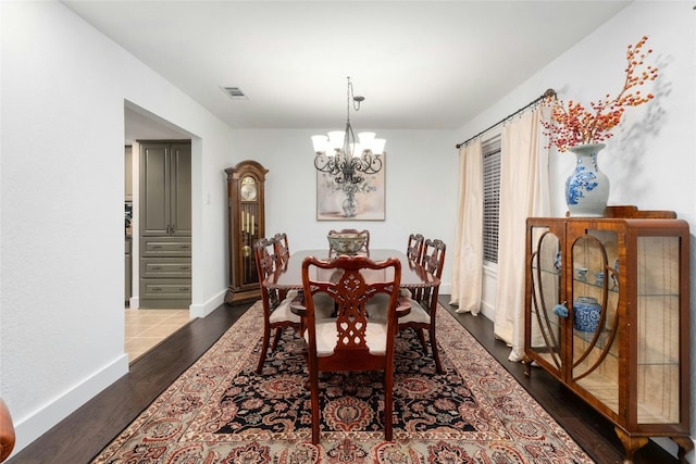 dining area featuring an inviting chandelier, wood finished floors, visible vents, and baseboards