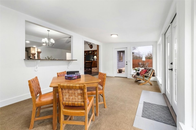 dining space with baseboards, light carpet, and a notable chandelier