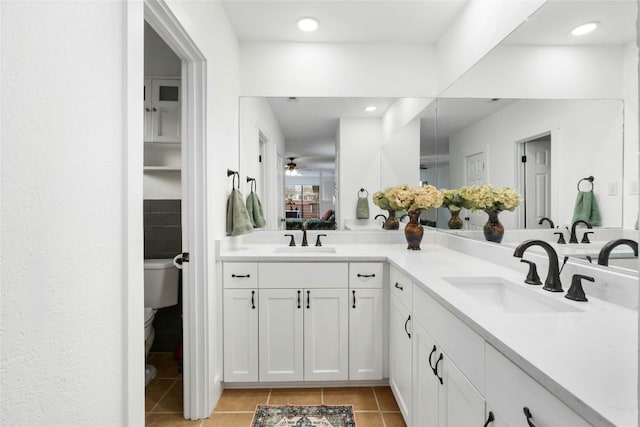 bathroom with tile patterned flooring, double vanity, toilet, and a sink