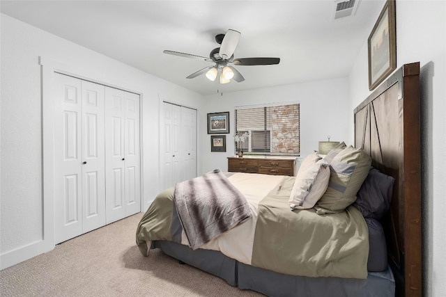 carpeted bedroom with ceiling fan, baseboards, visible vents, and multiple closets