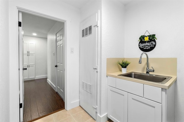 interior space featuring light tile patterned floors, baseboards, and a sink