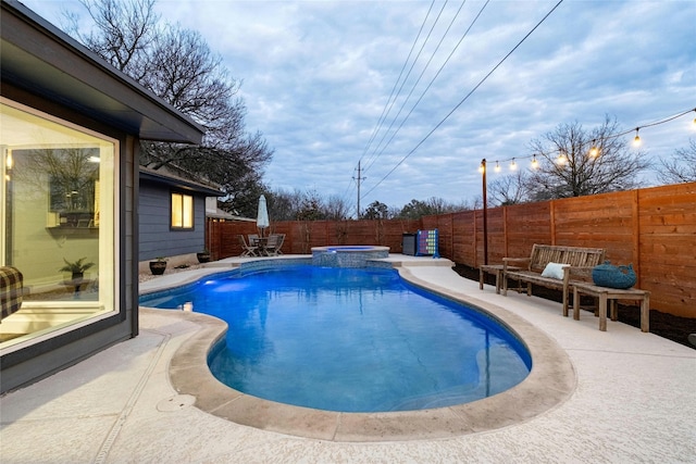 view of pool featuring a pool with connected hot tub, a fenced backyard, and a patio area