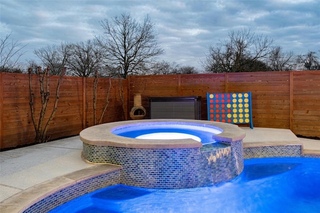 view of pool featuring an in ground hot tub and a fenced backyard