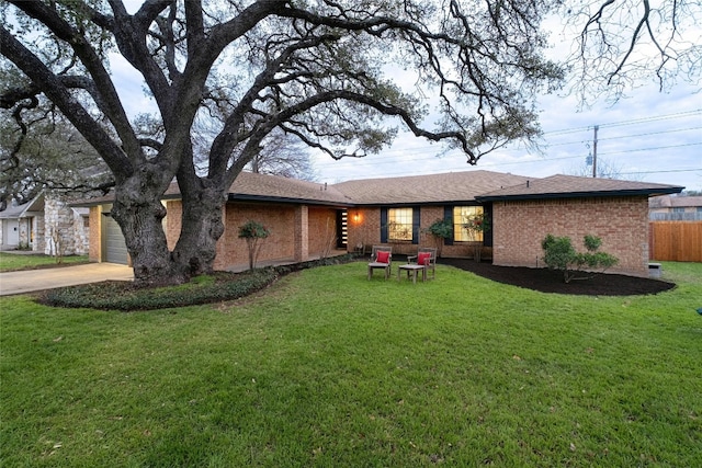 ranch-style house featuring a front lawn, fence, concrete driveway, a garage, and brick siding