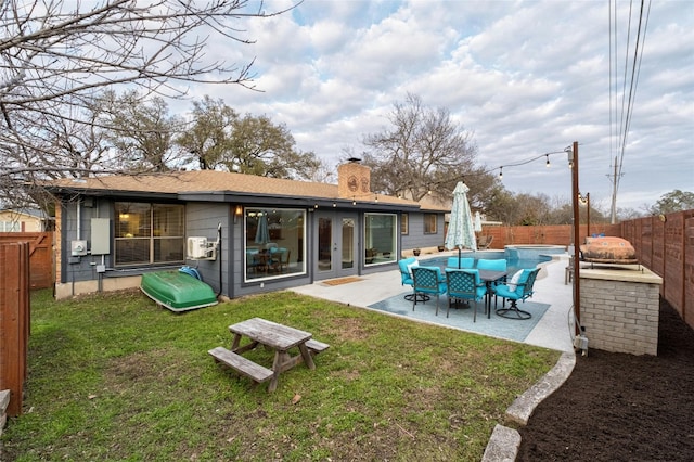 back of house featuring a fenced in pool, a lawn, a chimney, a fenced backyard, and a patio