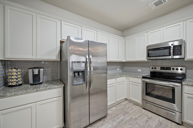 kitchen with white cabinetry, tasteful backsplash, stainless steel appliances, and light stone counters