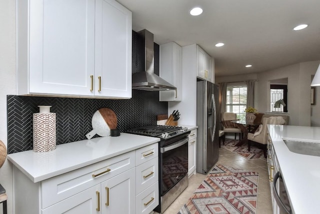 kitchen with appliances with stainless steel finishes, white cabinets, and wall chimney exhaust hood