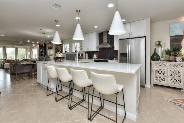 kitchen with white cabinetry, wall chimney exhaust hood, sink, and a large island with sink