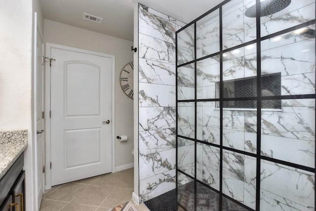 bathroom featuring tile patterned floors, vanity, and a tile shower