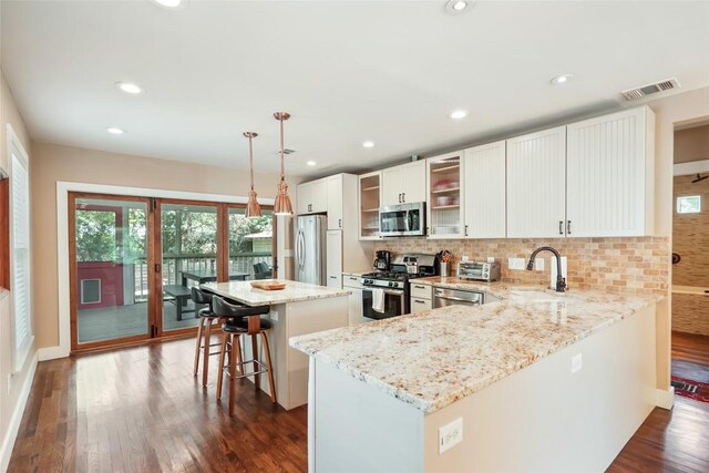 5719 Joe Sayers Ave, Austin, TX 78756 - kitchen with appliances with stainless steel finishes, decorative backsplash, dark wood-type flooring, a kitchen island, and a sink