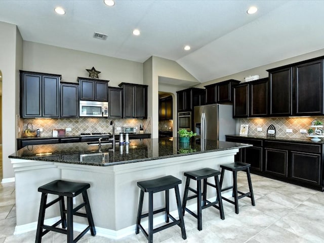1533 Cresson Trl, Leander, TX 78641 - kitchen featuring stainless steel appliances, lofted ceiling, a large island, a kitchen breakfast bar, and dark stone countertops