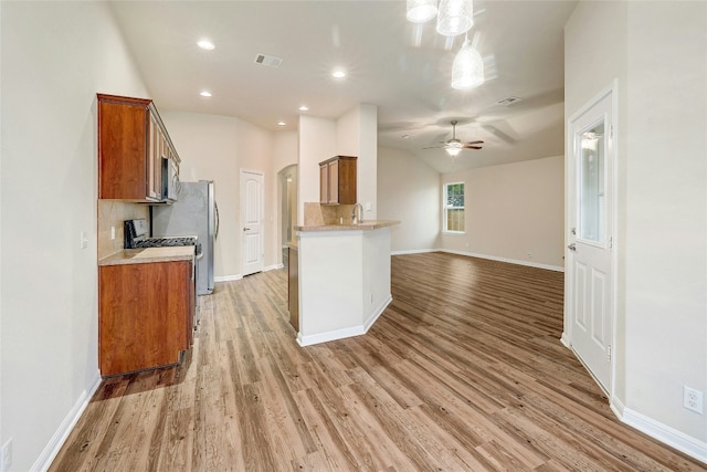 18825 Golden Eagle Way, Elgin, TX 78621 - kitchen featuring open floor plan, brown cabinets, arched walkways, light wood-style flooring, and recessed lighting