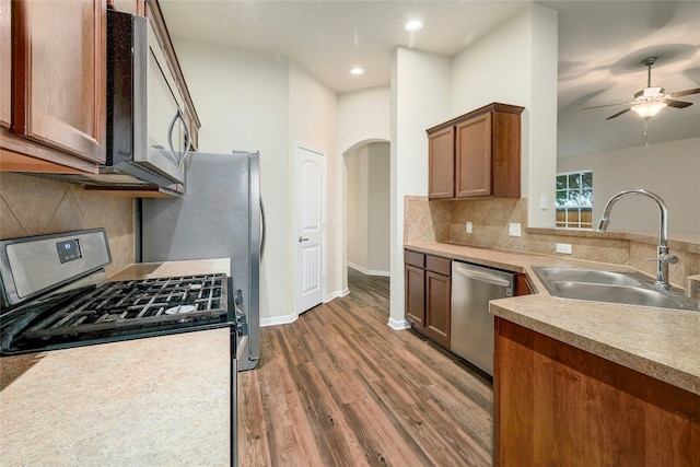 18825 Golden Eagle Way, Elgin, TX 78621 - kitchen featuring stainless steel appliances, wood finished floors, arched walkways, a ceiling fan, and backsplash