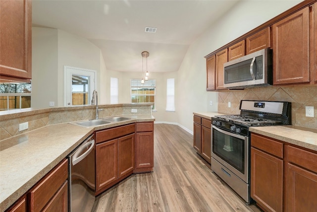 18825 Golden Eagle Way, Elgin, TX 78621 - kitchen with appliances with stainless steel finishes, light wood finished floors, lofted ceiling, decorative backsplash, and brown cabinetry