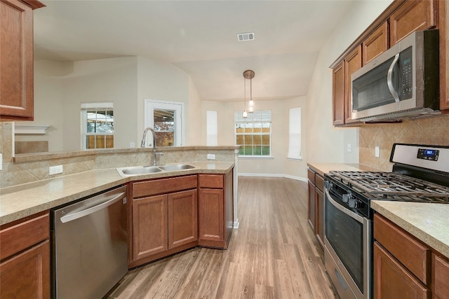 18825 Golden Eagle Way, Elgin, TX 78621 - kitchen featuring appliances with stainless steel finishes, light wood-style floors, tasteful backsplash, and brown cabinetry